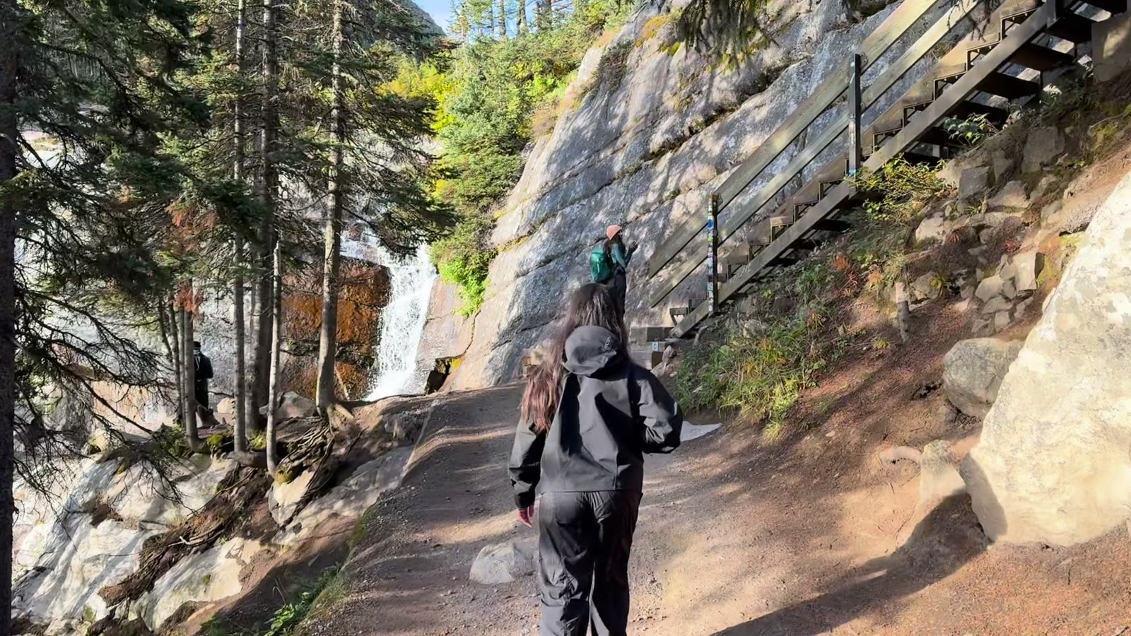 A hiker walking up a dirt path toward a small waterfall, shown over the line “what I want to do day to day, what I enjoy, how I stay creative”